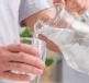 Image d’une personne remplissant un verre d’eau à partir d’une carafe en verre transparent.